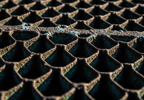Extreme close up of deeply corroded metal honeycomb mesh grate texture showing rust and patina photo