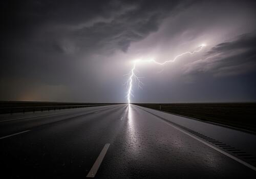 Powerful lightning bolt striking down onto a wet, dark interstate highway during a severe thunderstorm photo