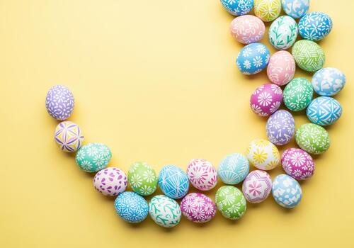 Colorful easter eggs with intricate white patterns arranged in a crescent shape on a yellow background. photo