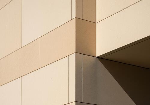 Clean architectural detail of a modern building corner with smooth beige stone blocks photo