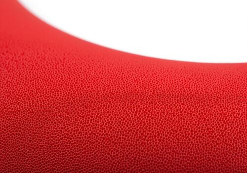 Detailed macro view of porous crimson red silicone texture on a curved surface photo