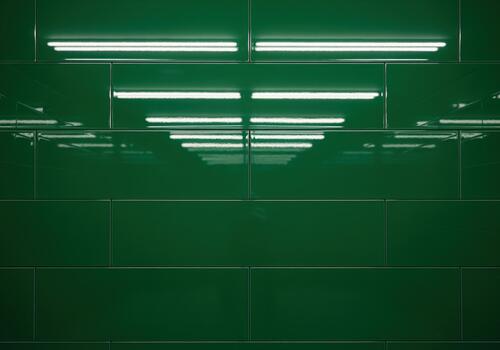 Emerald green glossy subway tile pattern reflecting bright overhead lighting photo
