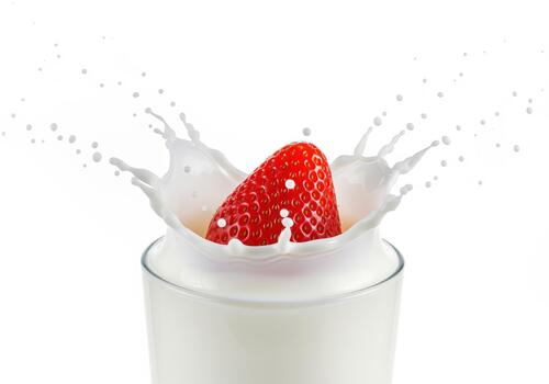 Bright red strawberry splashing into a glass of fresh white milk isolated on white background photo