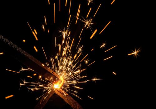 Dynamic shower of bright hot sparks flying from metal welding or grinding process. photo