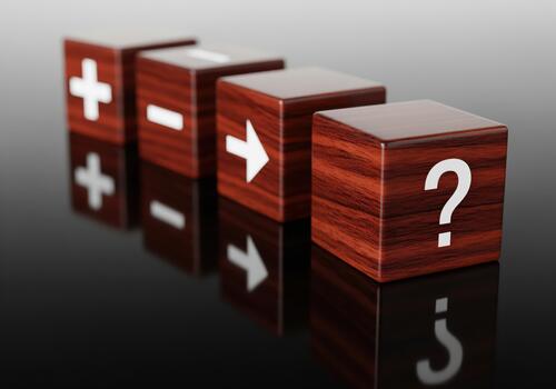 Four wooden blocks showing plus minus arrow and question mark symbols representing decision making process photo
