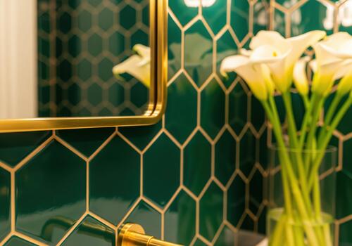 Luxurious emerald green hexagonal tile backsplash with gold accents and mirror frame photo