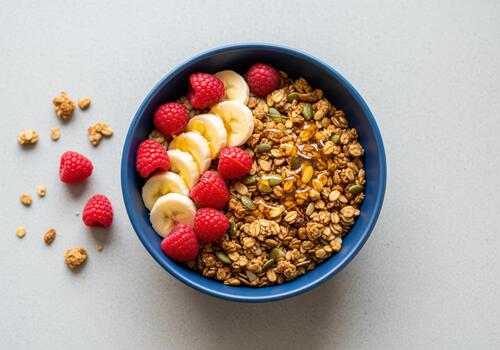 Overhead view of healthy granola breakfast bowl with fresh raspberries and banana photo