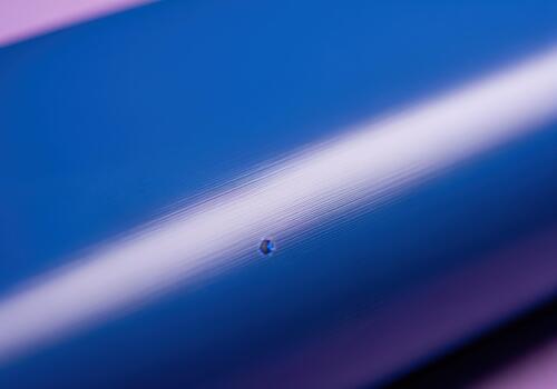 Macro detail of a vibrant electric blue surface with a bright diagonal light reflection and a tiny droplet photo
