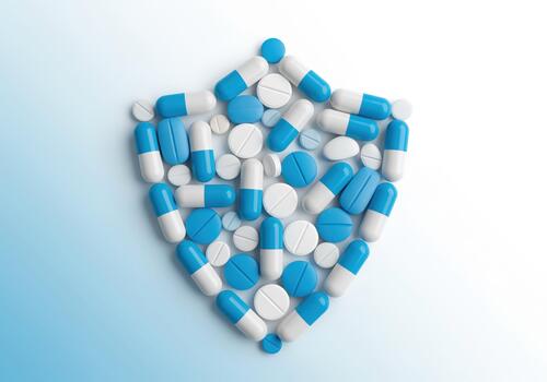 Blue and white pills and capsules arranged in a shield shape symbolizing health protection. photo