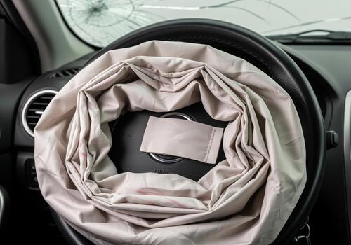 Deployed airbag on steering wheel after a car crash with windshield photo