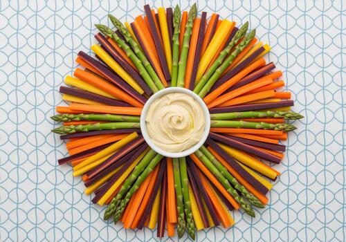 Rainbow carrots and asparagus spears with dipping sauce close up photo