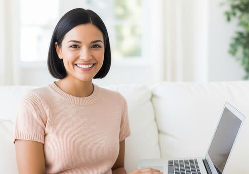 Happy young woman smiling brightly while working or browsing on a laptop computer at home. photo