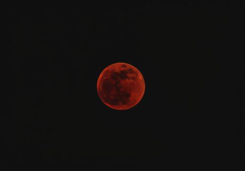 Striking view of a perfectly spherical blood moon during a total lunar eclipse against a black night sky photo