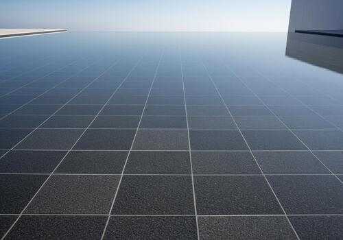 Pristine infinity pool surface with dark square tiles reflecting the clear blue sky photo