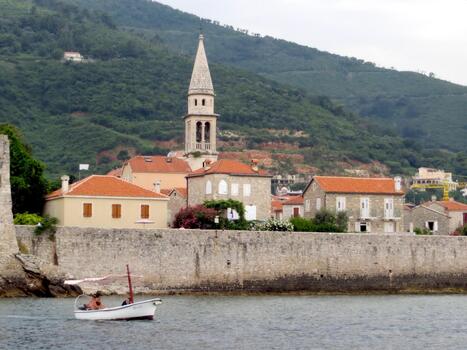 explorador Budas medieval pueblo en montenegro con un barco en tranquilo aguas foto