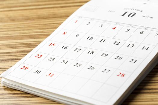 Calendar page for October displaying dates and days of the week on a wooden table photo