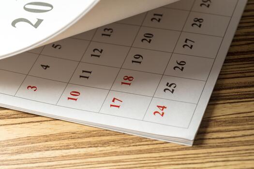 Calendar with marked dates resting on a wooden table in a well-lit setting photo