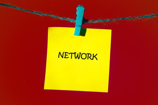 Bright yellow sticky note hangs on a blue string, boldly displaying the word network. The vibrant red background enhances the visual, symbolizing connection and opportunity photo