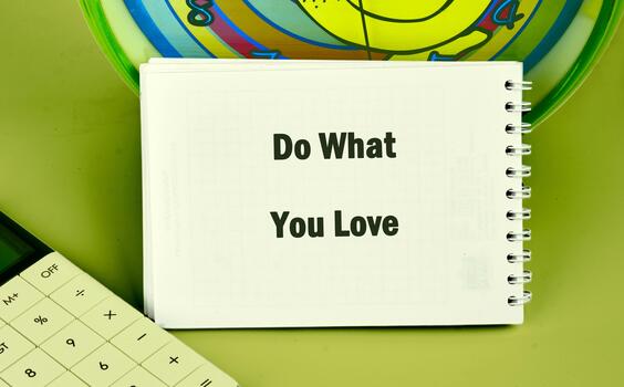 A notepad with the phrase Do What You Love sits on a desk alongside a calculator and a colorful spiral design. This setup encourages creativity and productivity during work hours photo