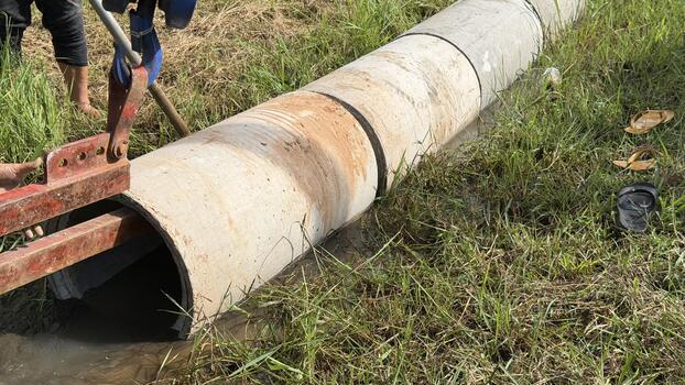 Workers using heavy equipment to install large concrete pipes for a new irrigation and drainage system in a field or farmland. Focus on water resource management and rural infrastructure construction. photo