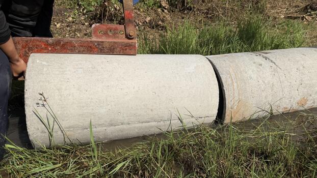 Workers are laying large concrete pipes in a trench to build an irrigation or drainage system in a rural area. Focus on infrastructure development and water management. photo