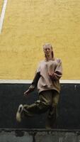 vertical . rua dançarino. atraente gen z jovem mulher dançando contemporâneo dança contra urbano amarelo e Preto parede video