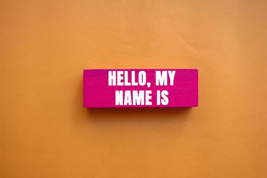 Hello, my name is message written on pink wooden block on orange background. Conceptual Hello, my name is symbol. Copy space. photo