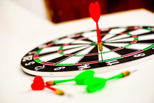 Close-up of dartboard with red dart in bullseye and other darts on surface, sharp focus photo