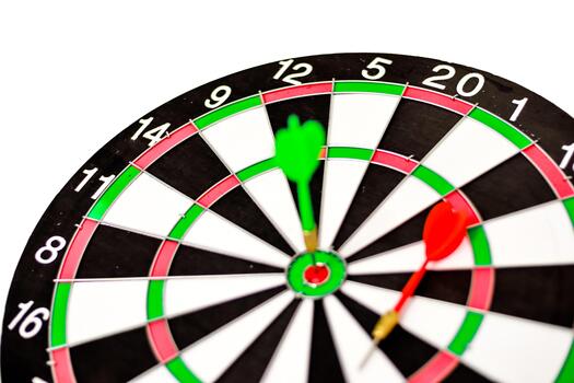 Close-up of dartboard with green dart in bullseye and red dart near 1 space illustrating precision targeting photo