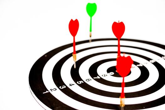 A target with two red darts in the bullseye and a green dart in the outer ring photo
