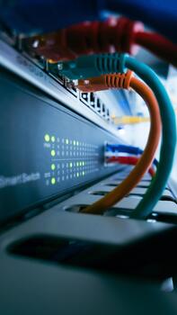 Vertical view of network switch with colorful ethernet cables and green LEDs, showing active data transmission and professional IT infrastructure. photo
