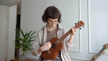 enfocado mujer jugando ukelele, experimentando con cuerda modelo y preocuparse posiciones, horda transición video