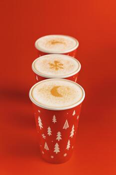 Christmas coffee cups with festive latte art on red background photo