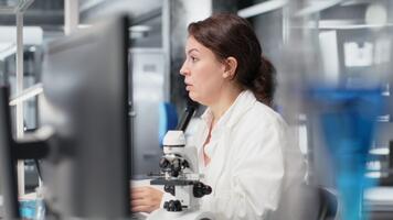 utmattad laboratorium molekyl biolog stretching på pc skrivbord, bearbetning dna patient data. trött labb anställd stängning ögon, tar ha sönder från genetisk analys på dator till koppla av, kamera b video