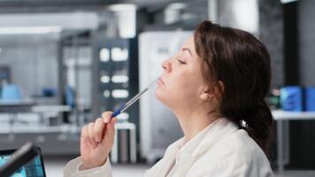 laboratorio científico lluvia de ideas ideas a computadora escritorio, frotamiento bolígrafo en mentón, esperando para datos a ser procesada. mujer en laboratorio haciendo pensamiento, interpretar laboratorio genético análisis diagnóstico, cámara si video