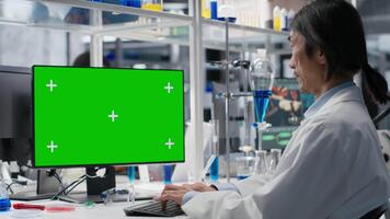 Sénior chercheur en utilisant vert écran ordinateur programme dans laboratoire, conduite traitement Découverte. asiatique employé en utilisant bioinformatique Logiciel sur chrominance clé PC dans stérile laboratoire video