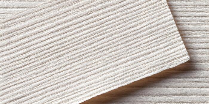 Two overlapping cream paper sheets with a distinctive ribbed texture form a clean background photo