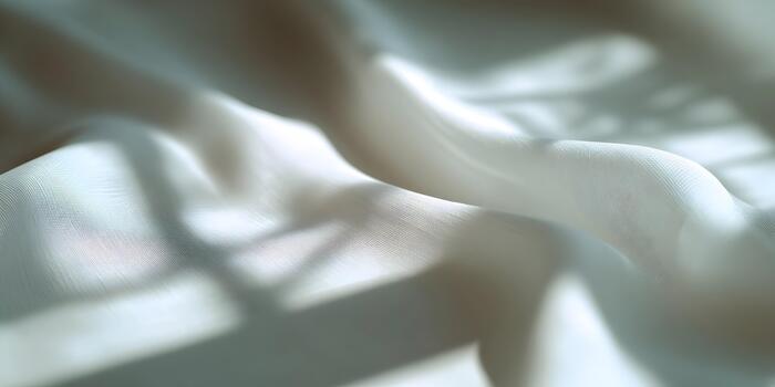 Soft flowing white fabric drapes with natural shadows creating an elegant abstract background photo