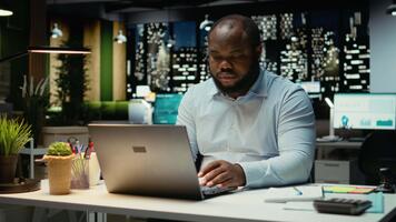 African american analyst focusing on a complex problem in a dark office at night, strategizing and envisioning options with laptop open. Seeking a logical solution through deduction. Camera A. video