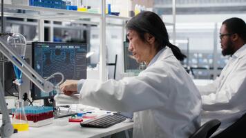 Scientist uses laboratory lamp to examine test subject in petri dish. Research facility technician holds medical container to light source, monitoring samples for impurity detection, camera B video