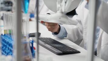 laboratorio professionale esamina test tubo campione sotto controllato illuminazione per trasparenza e consistenza. scienziato usi lampada illuminazione per osservare liquido proprietà e individuare impurità, telecamera B video