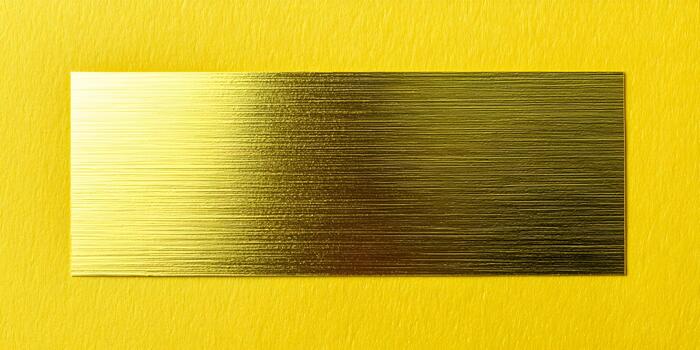 A golden rectangular plate with horizontal brushed texture is centered on a vibrant yellow textured background photo
