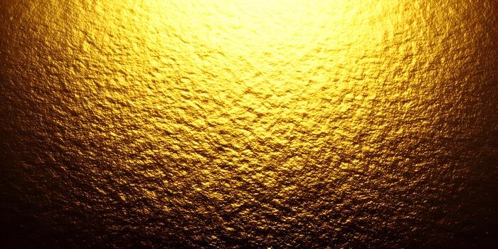 A bright golden textured surface with light shining from above creating a rich and opulent abstract background photo