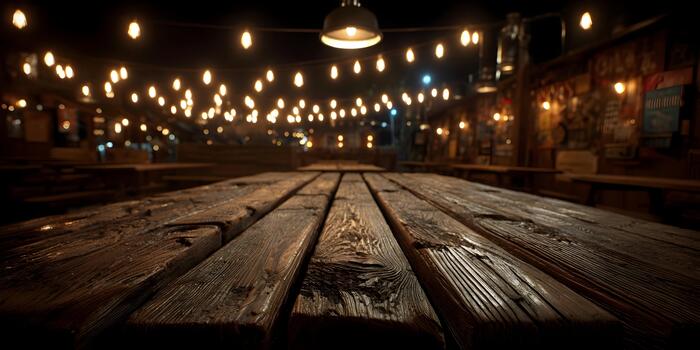 Rustic wooden table surface with warm blurred string lights creating a cozy evening atmosphere photo