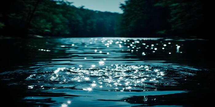 Sunlight creates a mesmerizing bokeh and starburst effect on a dark river surface with a blurred forest backdrop photo