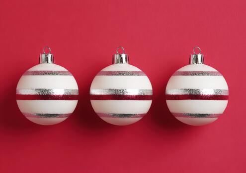 Three round ornaments hang against a vibrant red backdrop photo