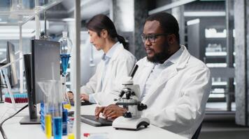 investigador utilizando computadora solicitud a revisión paciente datos en laboratorio. investigación instalaciones especialista utilizando bioinformática genómica software en ordenador personal en laboratorio, analizando resultados, cámara si video