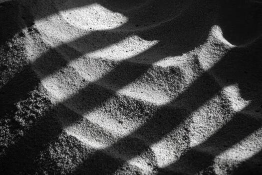 Shadows create patterns on soft sand surface photo
