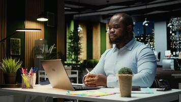 svart företag konsult sammanfogning ett uppkopplad ring upp möte efter timmar, engagerad i webb diskussion med aktieägare. professionell kille interagera med människor i nätverkande session. kamera a. video