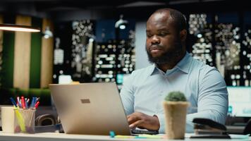 nero dipendente lettura messaggi di posta elettronica e documentare dati a partire dal ragnatela intuizioni per un' multinazionale azienda, Lavorando dopo ore nel un' buio ufficio. impresa obiettivi e sviluppo. telecamera b. video